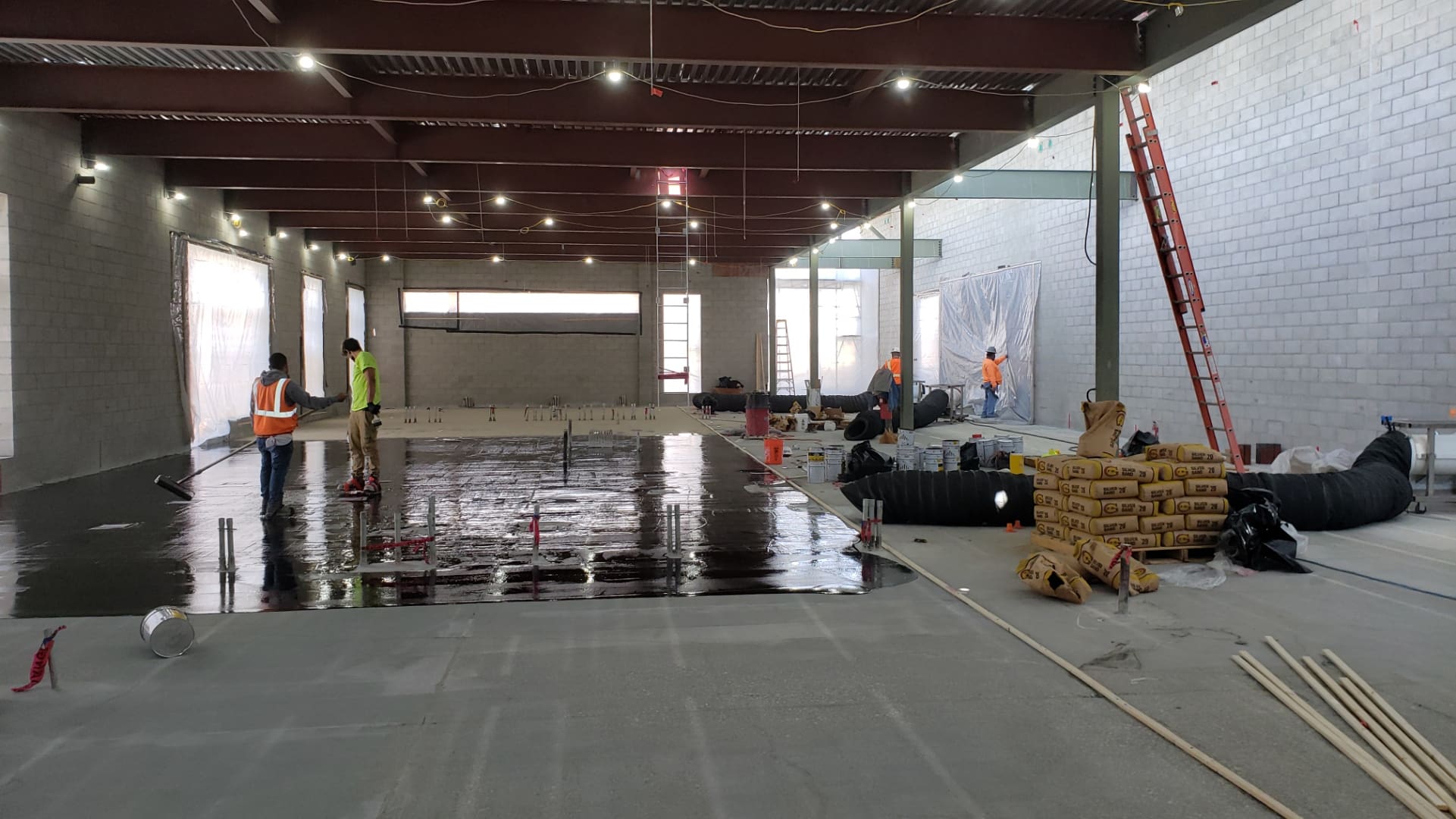 Construction workers applying sealant to floor.